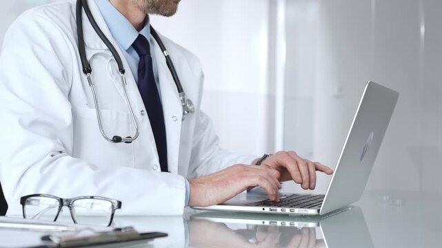 Doctor typing on a laptop, providing online consultation and healthcare services, modern medical technology. Medicine, healthcare and science concept
