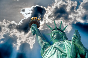 Eingescanntes Diapositiv einer historischen Farbaufnahme der Freiheitsstatue in New York in extremer Unteransicht bei sonnigem Wetter und dramatischem Himmel