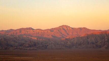 Naklejka premium Majestic mountain range bathed in warm golden hour sunlight