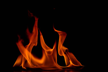 Clustered dense flames arranged together against black background with vibrant orange and red...