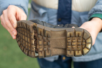 Torn Boot. A man holds an old boot in his hands.