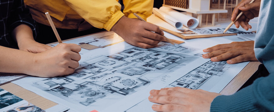 A dynamic scene showcasing hands actively engaged in sketching architectural plans during a collaborative design session in a bright and creative workspace. SACTR