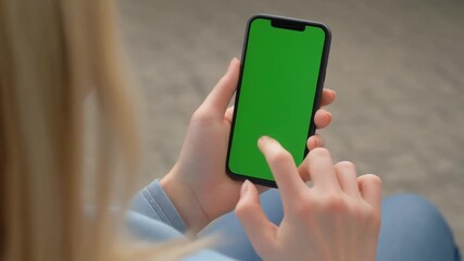 Woman using smartphone with a green screen display, tapping and swiping for app interaction and digital content mockup. - Powered by Adobe
