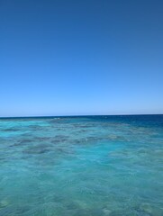 Fototapeta premium Horizon of Tranquility: A breathtaking vista of ocean meets endless sky. Clear, crystalline water reflecting the endless blue above evokes a sense of peace and serenity.