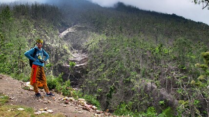 The guy stands against the background of a tropical forest. Adventures in Southeast Asia