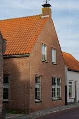 Cozy brick house with orange tiled roof, classic architecture and street view.