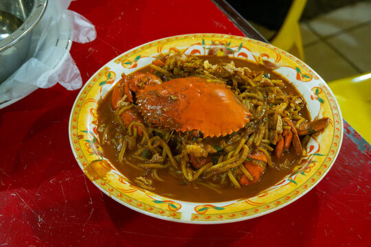 a plate of mie aceh kepiting nyemek, a traditional dish from Aceh, Indonesia, noodle with thick spicy soup and a whole crab for protein