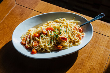 Delicious spaghetti with tomatoes and herbs served on a white plate.