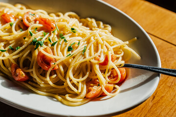 Delicious plate of spaghetti with fresh cherry tomatoes and green herbs.
