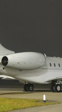 white unmarked private jet designed for haul flights parked apron fbo gat stands aircraft during dark night airport long panning shot long-haul 