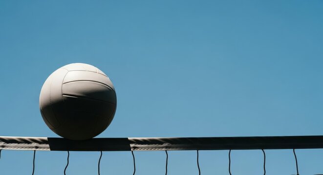 Volleyball Resting on Net Against Clear Blue Sky