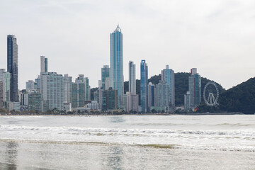 Beach with white sand and trees and buildings in the background in Balneario Camboriu, Santa Catarina, Brazil.