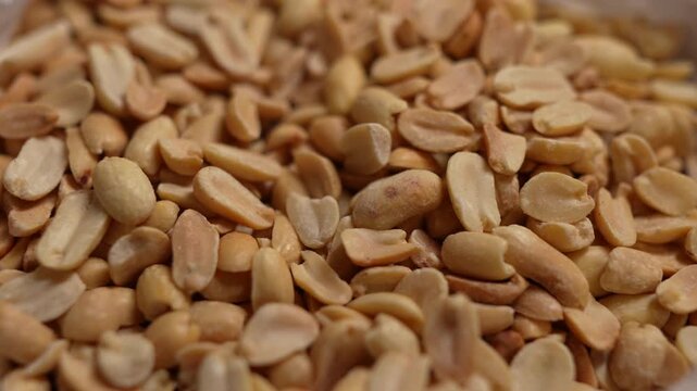 Spicy flavored peanut kernel spilling on white table background.