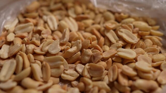 Spicy flavored peanut kernel spilling on white table background.