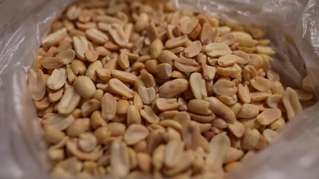 Spicy flavored peanut kernel spilling on white table background.