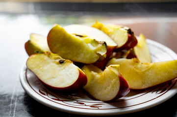 Fresh red apples cut into slices and served on a plate placed on a table.