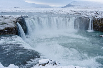 Majestic waterfalls cascade powerfully through the snowy, winter landscape.