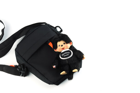 cute plush dolls key chain hang with black hand bag  , Monchichi or Monchhichi , Japanese cute monkey fur doll display on white table white wall background in souvenir gifts tourists shop Japan dolls