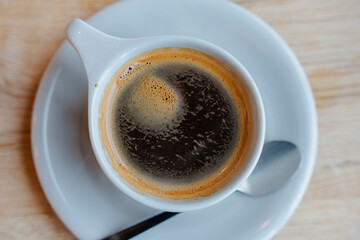 A delicious cup of coffee served in a white cup with a white saucer.