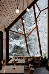 Cozy dining room with a view of snow-covered trees through large windows.