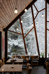 Cozy eatery setting with a view of snow-covered trees through pane windows.