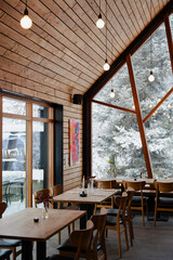 Inviting restaurant interior with natural wood and a snowy winter view.