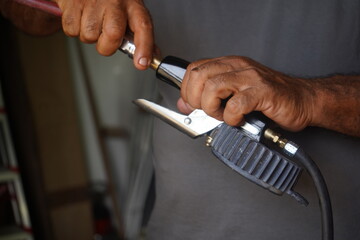 Mechanic's hands connect an air gauge to an air hose, performing tire inflation or pressure check for an automotive workshop task.