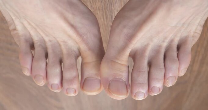 Feet and toes of an adult man. Beautiful male feet with uncut nails. Ten toes on two feet. Man wiggles his toes