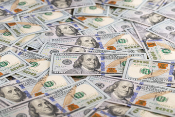 Close Up Gold Bar Shaped Like US One Hundred Dollar Bill on Scattered Cash Background