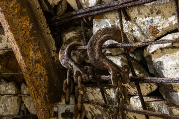 Heavy tools and equipment inside an underground mine, with steel chains, pneumatic hoses, and supply lines in active use. The scene shows industrial work conditions, mining technology, and harsh subte