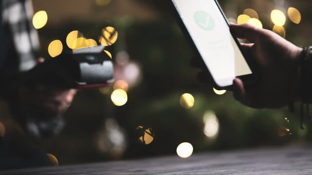 Waitress Holds A Wireless Terminal As A Girl Pays With Smartphone, Processing And Approving The Payment On The Screen
