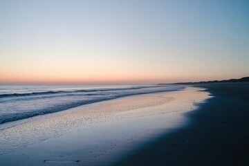 The ocean waves gently wash onto the sandy shore during a beautiful pastel sunset.