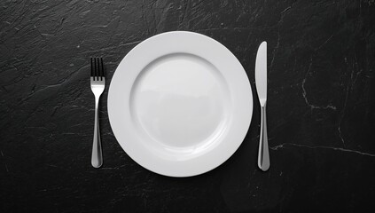 Table arrangement featuring an empty plate and cutlery set against a black stone backdrop, background for text and layout