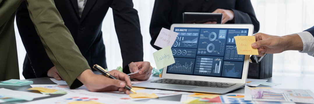 Analyst team use sticky note for creative and analytic brainstorm for business idea with BI data dashboard on laptop screen. Analysis financial data visualization tech for marketing strategy. Prodigy - Powered by Adobe