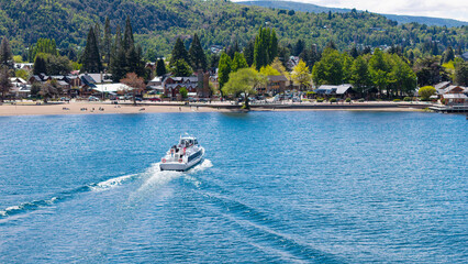 A tourist boat sails on Lake Lacar, with the city of San Martin de los Andes in the background.