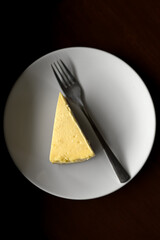 Appetizing Overhead Shot of Triangle Cheesecake Slice on Plate with Fork Still Life