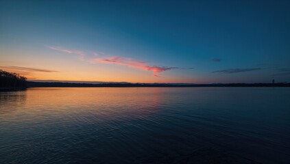 Obraz premium Sunset over a lake shoreline, emphasizing natural beauty and serenity