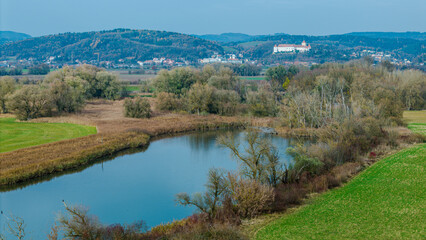 Landschaft am Fluss mit Blick auf die Hügel und ein Schloss im Hintergrund, bei Tageslicht in...
