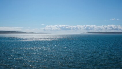 Serene blue ocean beneath a bright sky at a northern shoreline, showcasing seasonal change