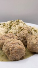 Cooked meatballs with sauce and rice on a plate closeup. Traditional Polish dinner, European cuisine, vertical view