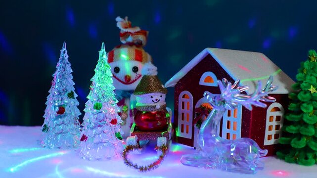 Near the red Christmas house there are snowmen, Christmas trees and a glass figurine of a deer