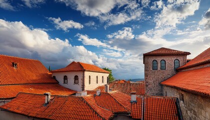 historical buildings featuring traditional architecture with orange tiled roofs under a partly cloudy sky