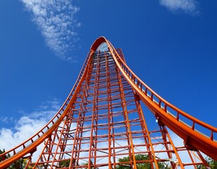 Obraz premium orange rollercoaster track against a bright blue sky curving and reaching upward promising thrill and adventure