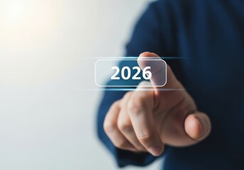 Hand presses a glowing digital button with the number 2026 on a screen