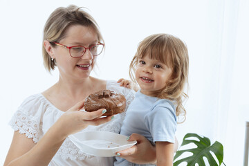 A mother giving her child a chocolate-glazed donut, an unhealthy feeding practice with food full of sugar.