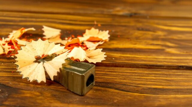 Close-up of pencil sharpener and shavings on a wooden surface, highlighting texture