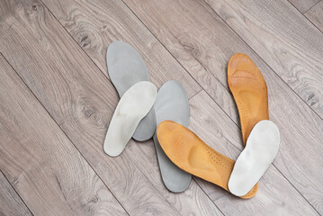Adult and children orthopedic insoles on the room floor and in footwear showing family foot care and early valgus prevention