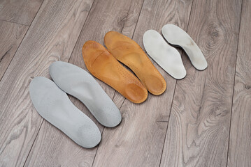 Adult and children orthopedic insoles on the room floor and in footwear showing family foot care and early valgus prevention