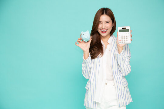 Happy young Asian woman holding calculator and piggy bank isolated on green background, Business and financial concept - Powered by Adobe