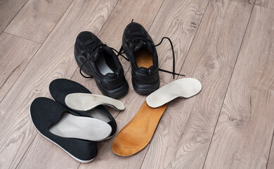 Adult and children orthopedic insoles on the room floor and in footwear showing family foot care and early valgus prevention